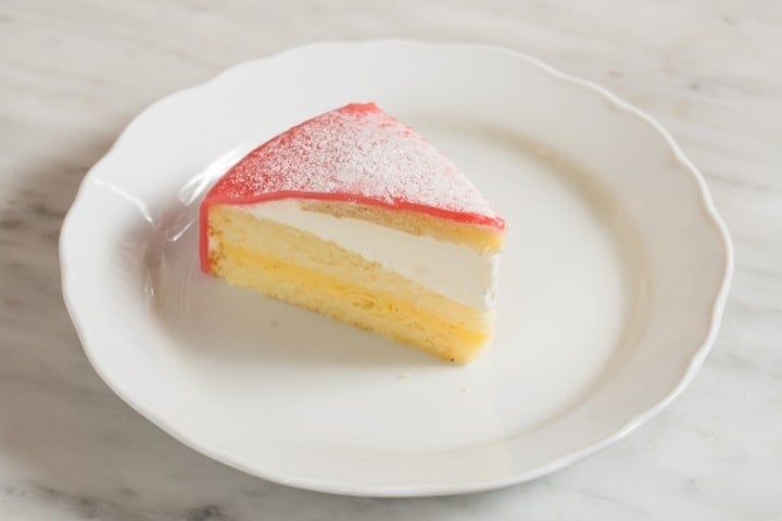 a slice of yellow cake with pink marizpan frosting