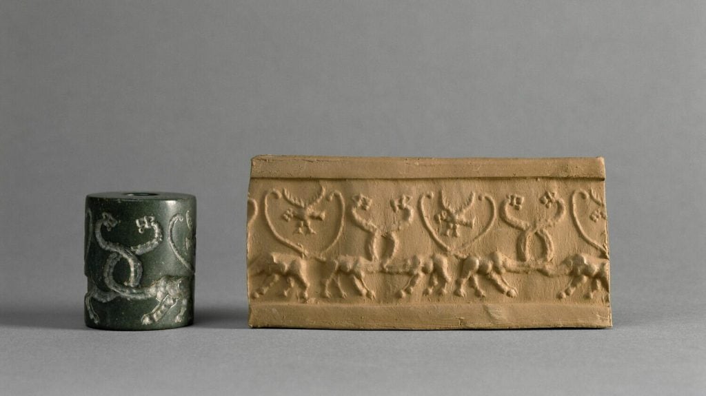 A photograph of a cylinder seal with a pattern embossed into it, and a yellow piece of clay to the right bearing its stamp, all on a gray background.