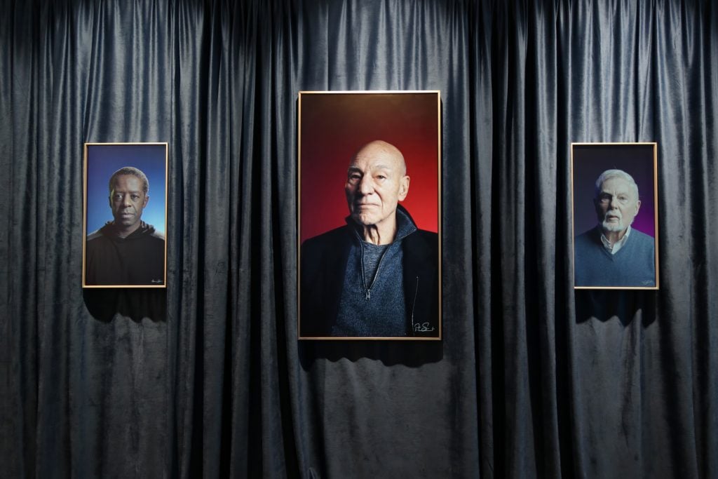 a curtained room with three portraits left to right