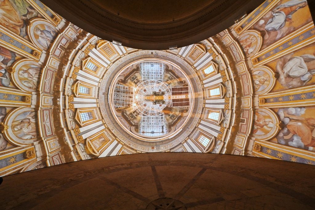 A screen showing a digital rendering of the ornate ceiling of St. Peter's Basilica