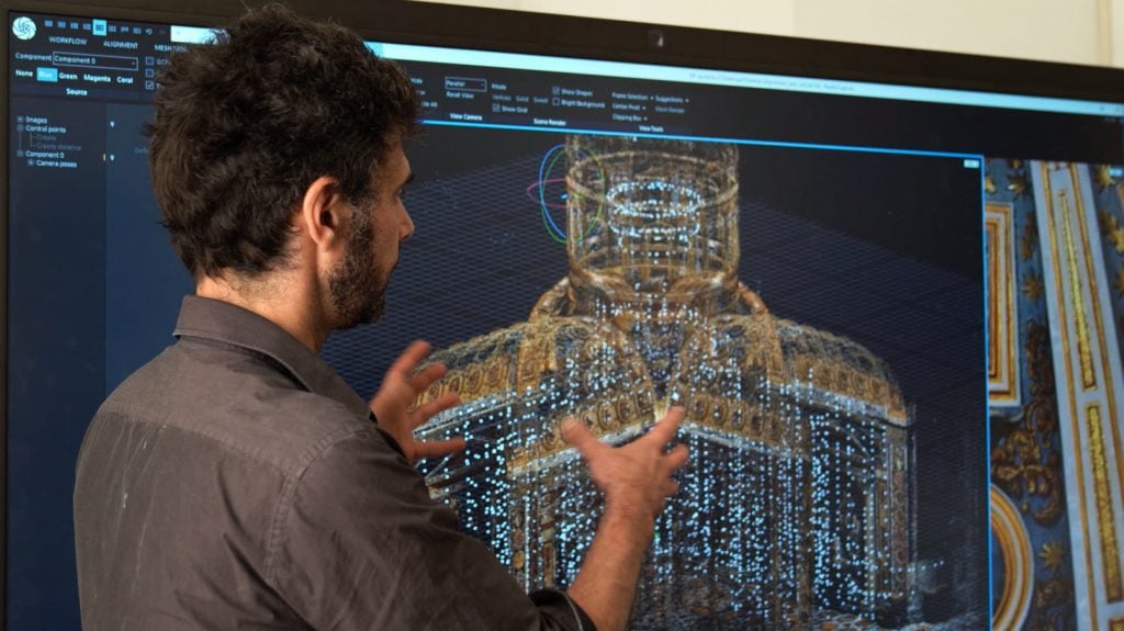 A man standing in front of a screen showing a digital rendering of St. Peter's Basilica