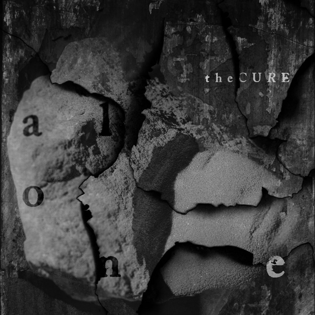 Album cover for the Cure's "Alone," featuring a cracked sculpture of a head overlaid with various other stone textures