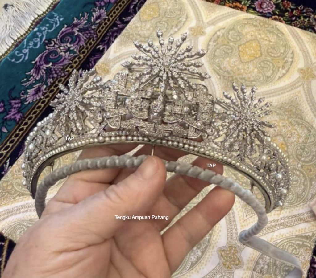 a diamond tiara held by a hand above a carpeted floor