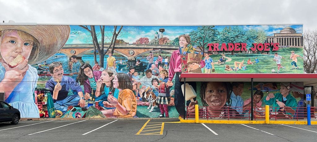 The facade of a Trader Joe's store covered in a long painted mural depicting a bright park scene