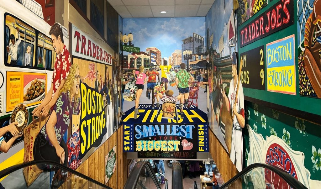 Brightly colored Trader Joe's signs and murals surround a downward escalator