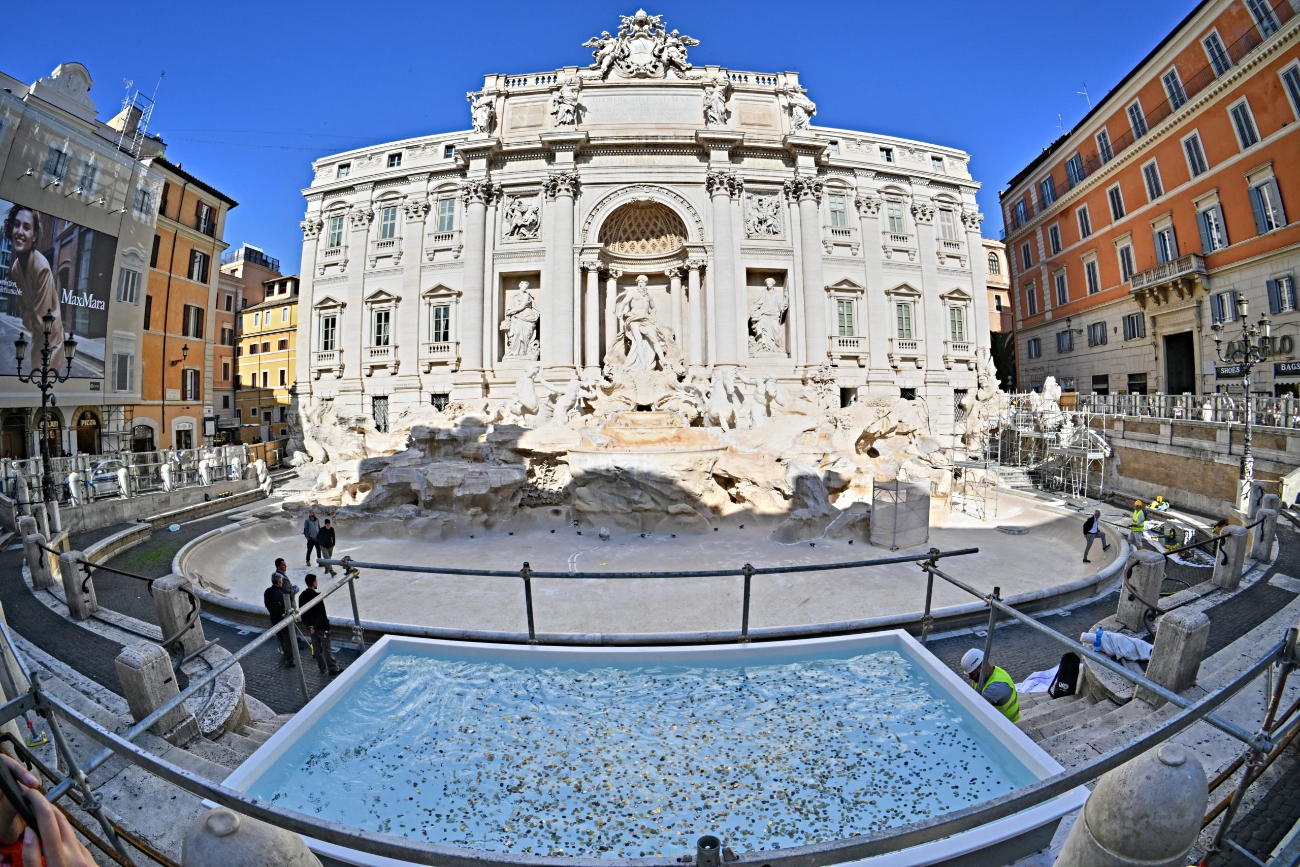 Wide angle photo of the Trevi Fountain in Rome, which is dry, with a makeshift pool in the front