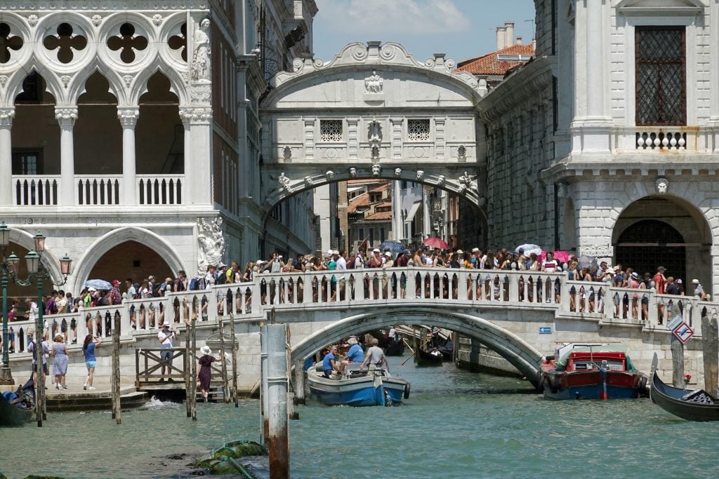 Tourists crowded together cross the Bridge of Sighs (Ponte dei Sospiri) in Venice.