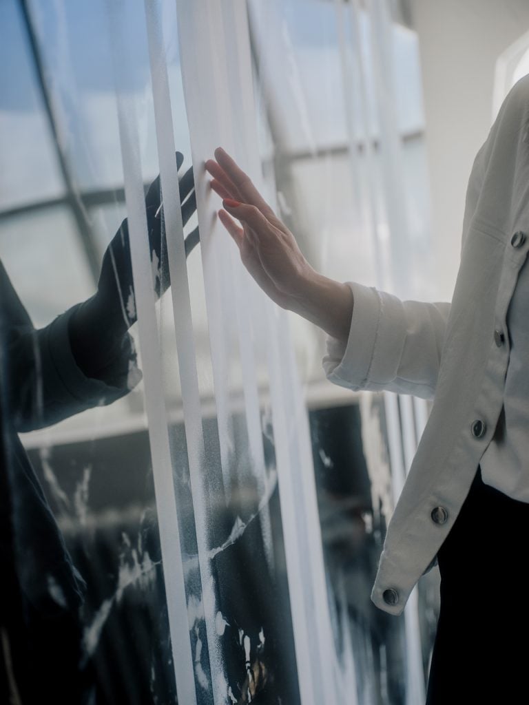 a woman named Ruscha Voormann walks among her black and white abstract paintings