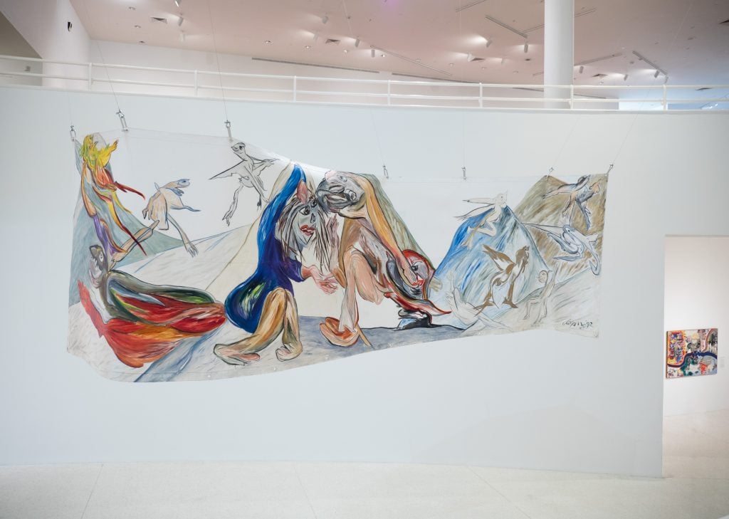 an instllation view of a flowing white paper sculpture covered in colorful drawings