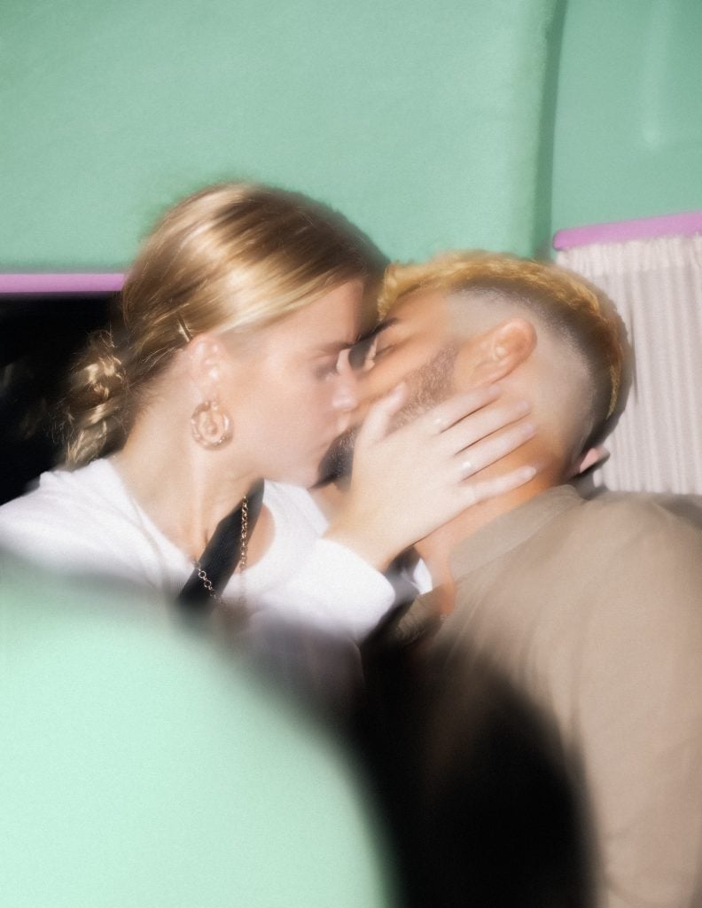 A blurry photograph of a young ​couple kissing