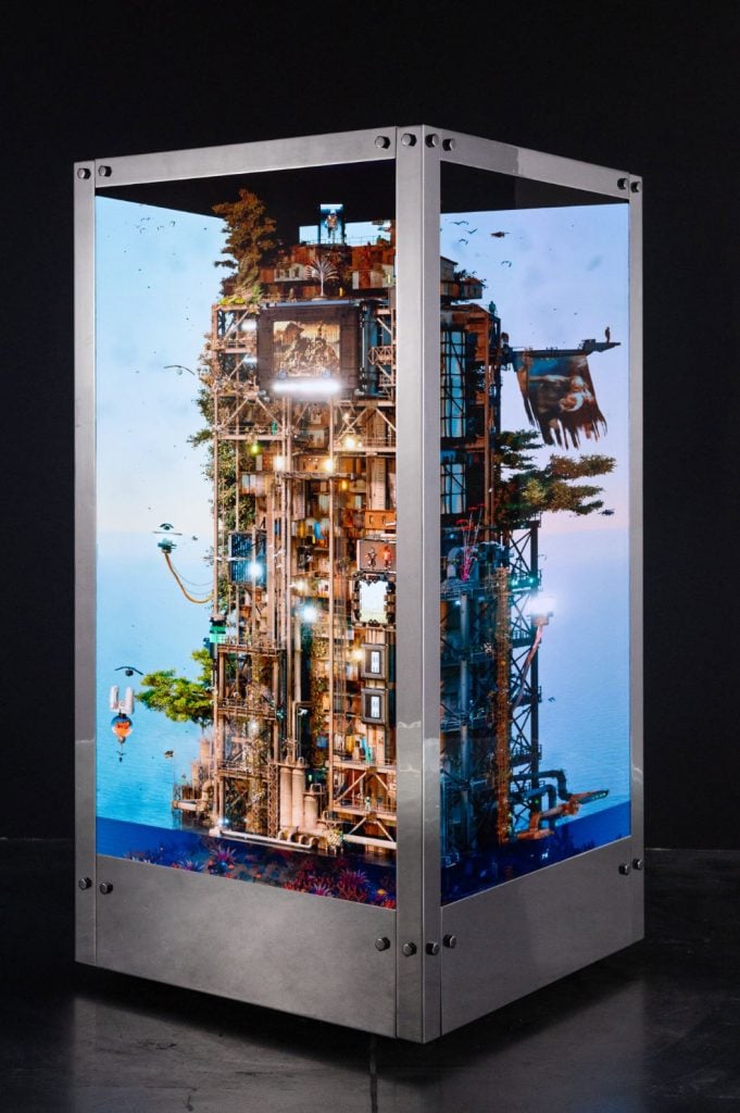 a sculpture made up of two rotating cubes with screens showing a tower on a blue sky background