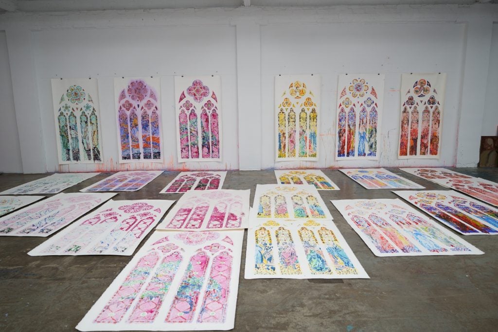 Claire Tabouret's sketches for her stained glass window designs for Notre Dame Cathedral in Paris. The colorful window designs are painted in watercolor on white paper, hung on the wall and laid out on the floor. 