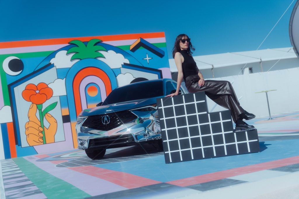 a woman in all black is on a 90s art installation car activation. 