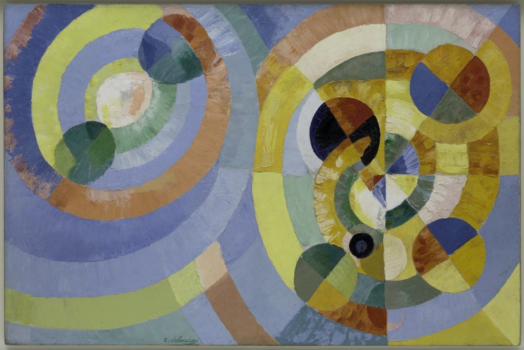 A largely pale blue and orange abstract painting made up of concentric circles.