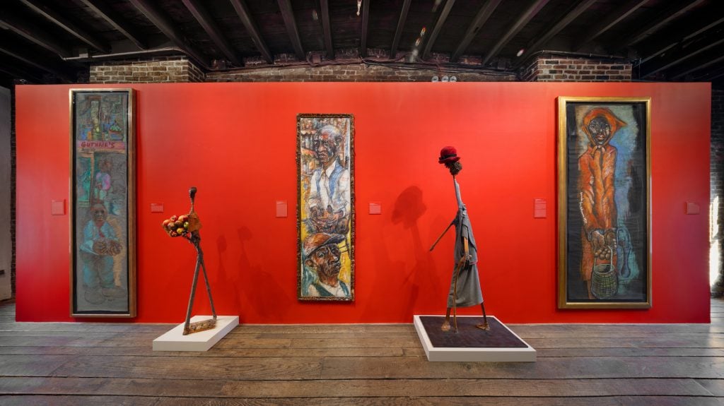 an image of Aminah Robinson artwork installed at the gallery against the backdrop of red walls