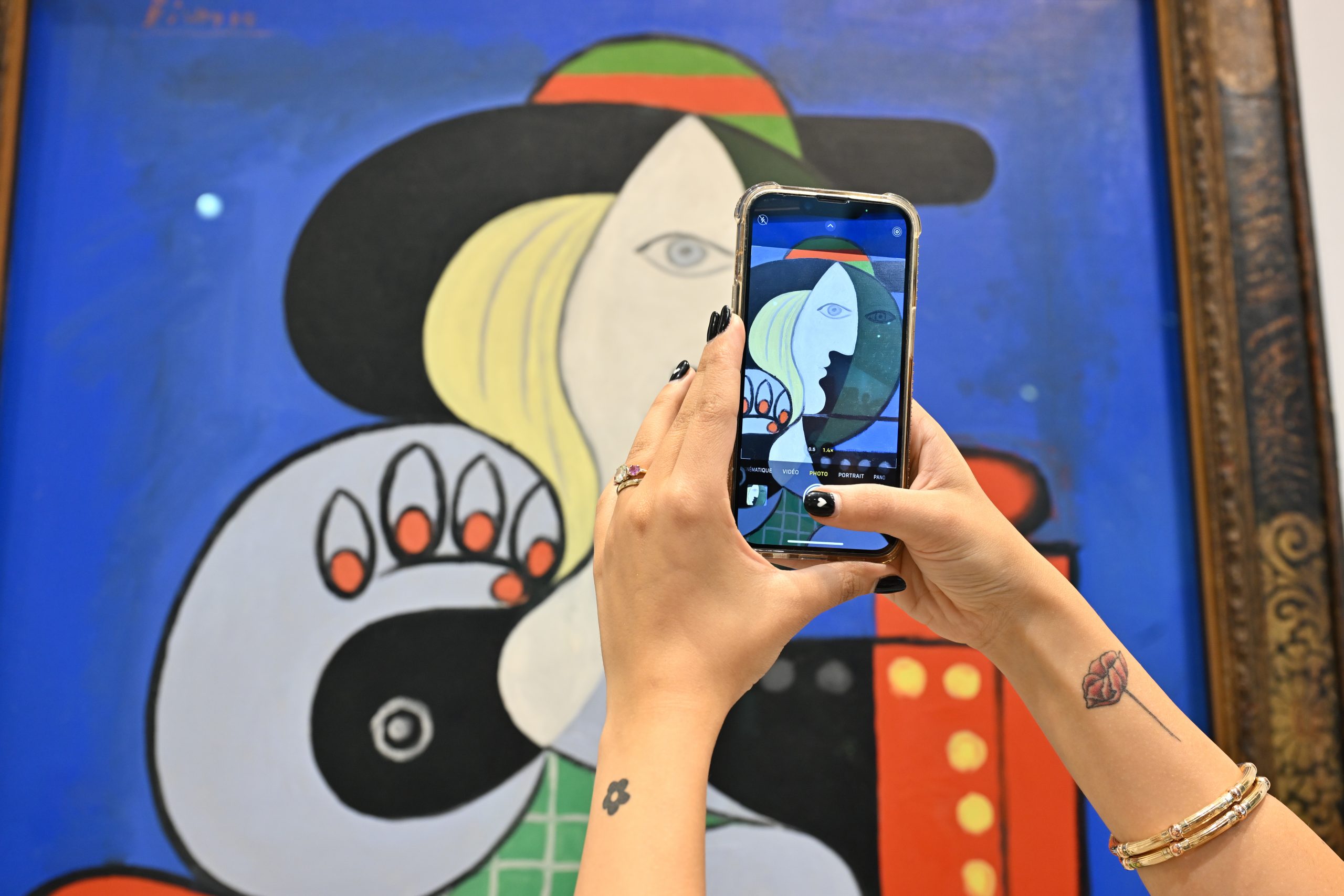 A person takes a photo of a colorful abstract painting with their smartphone,