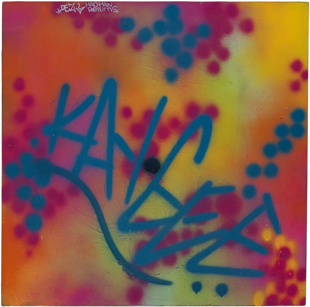 A spray-painted painting in reds and yellows, with the tag "KAYGEE" in dark blue