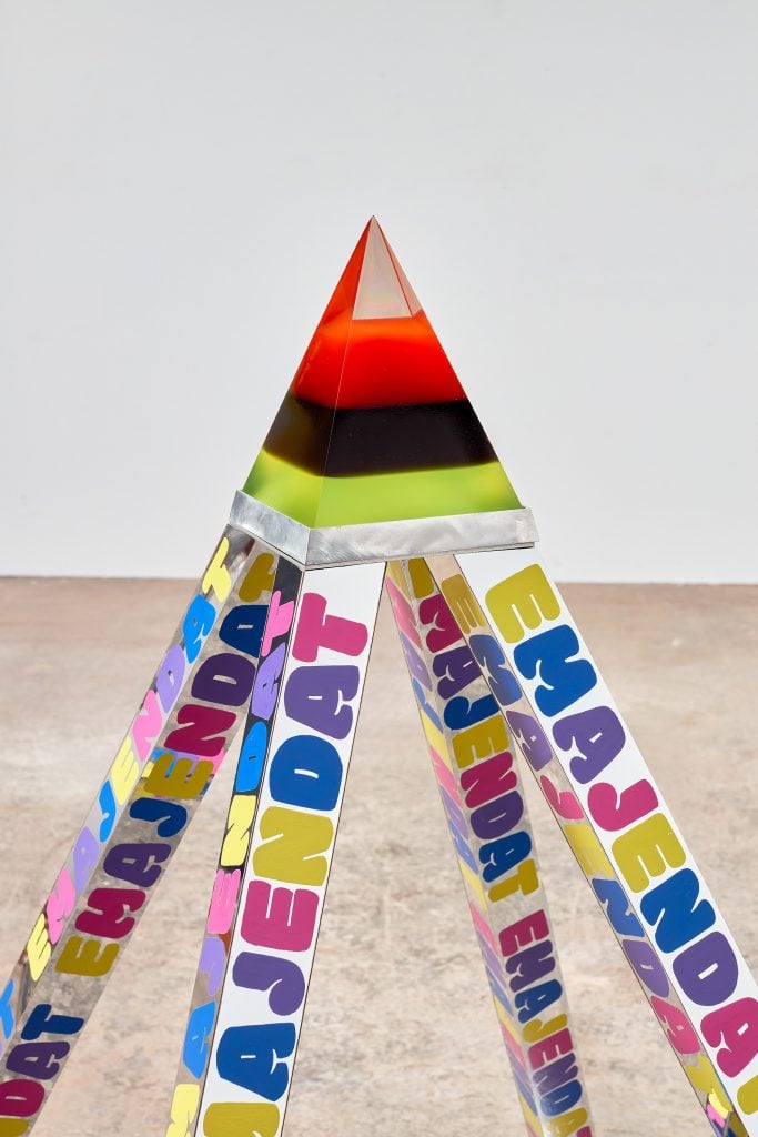 a red black and green crystallin pyramid is atop a tripod in an art piece by Lauren Halsey 