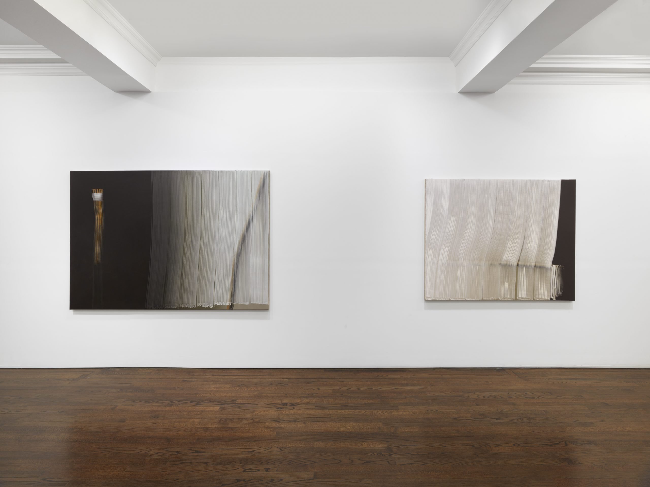 Two black and white paintings glow on a wall