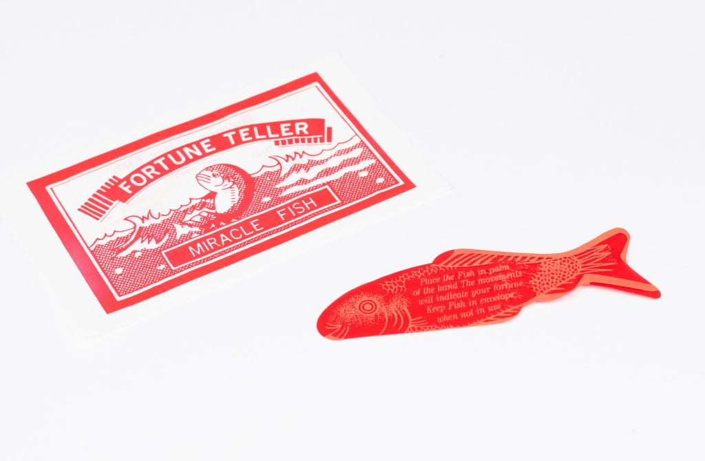 A red label that says Fortune Teller Miracle Fish, and a flat piece of paper in the shape of red fish