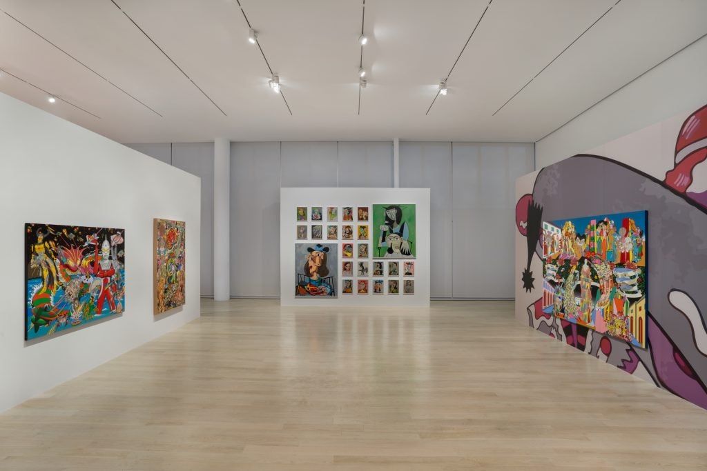 colorful paintings are displayed in airy, high-ceilinged space