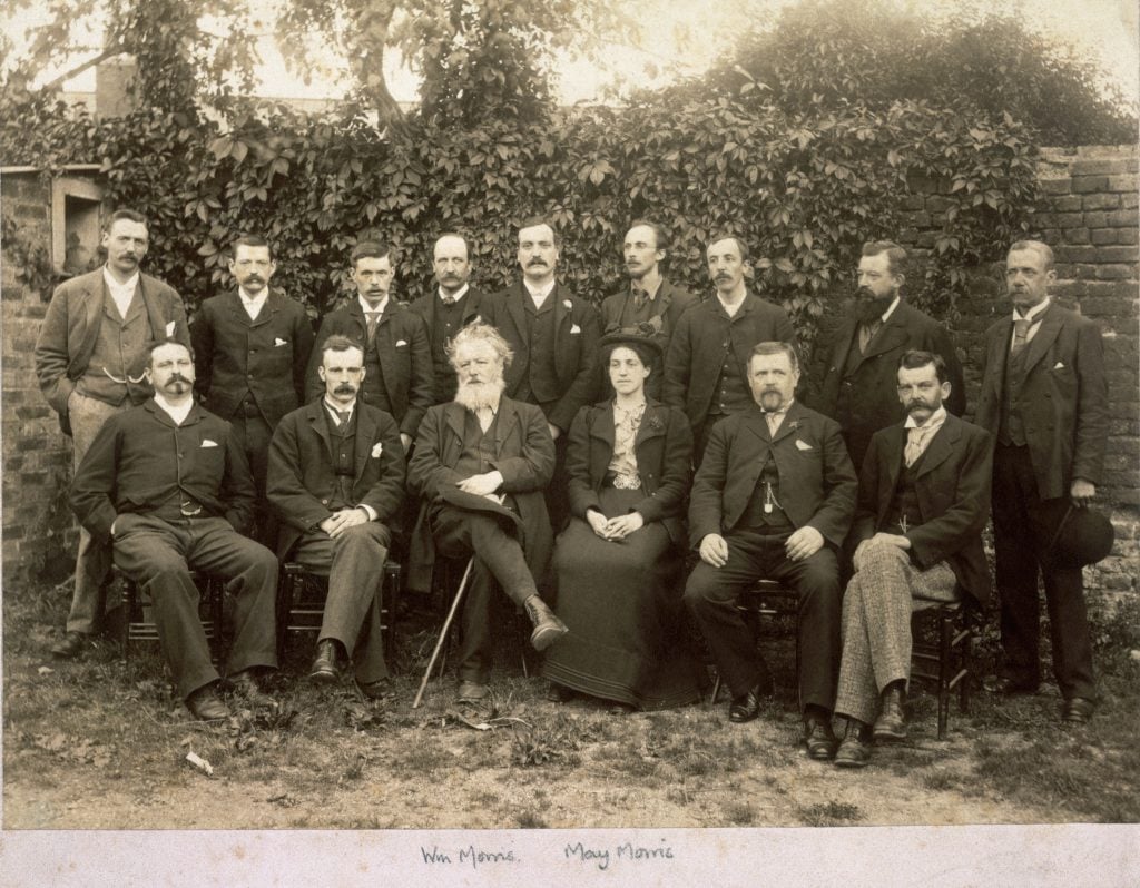 black and white photo of men posing for a group photograph with one woman in the center