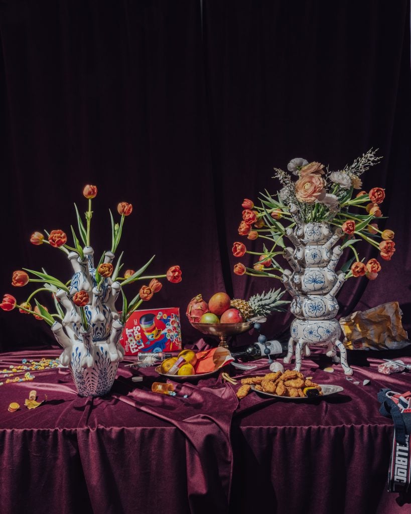 a table setting has a dark background and ceramics and flowers atop