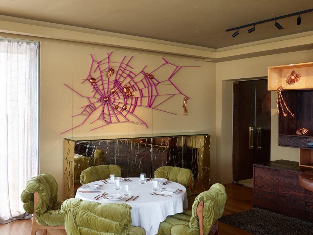 a dining room has a maroon web sculpture on wall