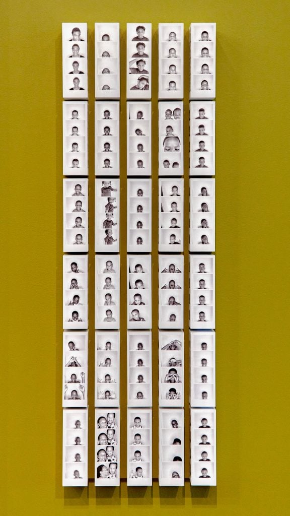 a series of Photo Booth images depicted on a mustard wall show black haircuts 