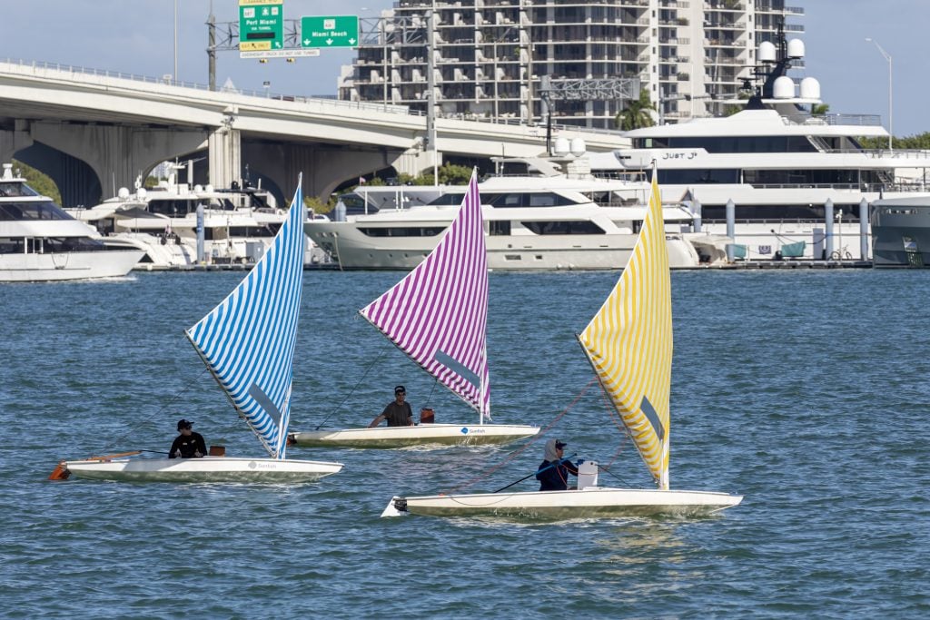 Three sailboats with colorful striped sails on the water