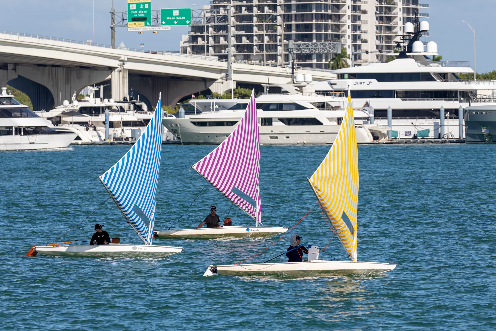 Three sailboats with colorful striped sails on the water