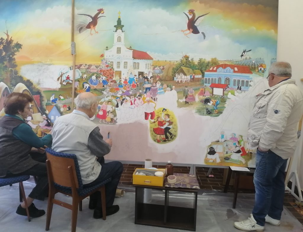 a group of old men are seen from behind painting a large scale painting in a naive folk art style