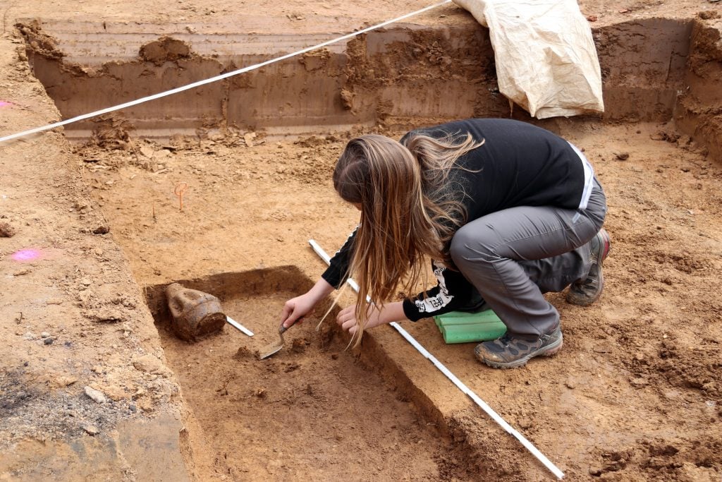 woman digging up a grave in a sand pit