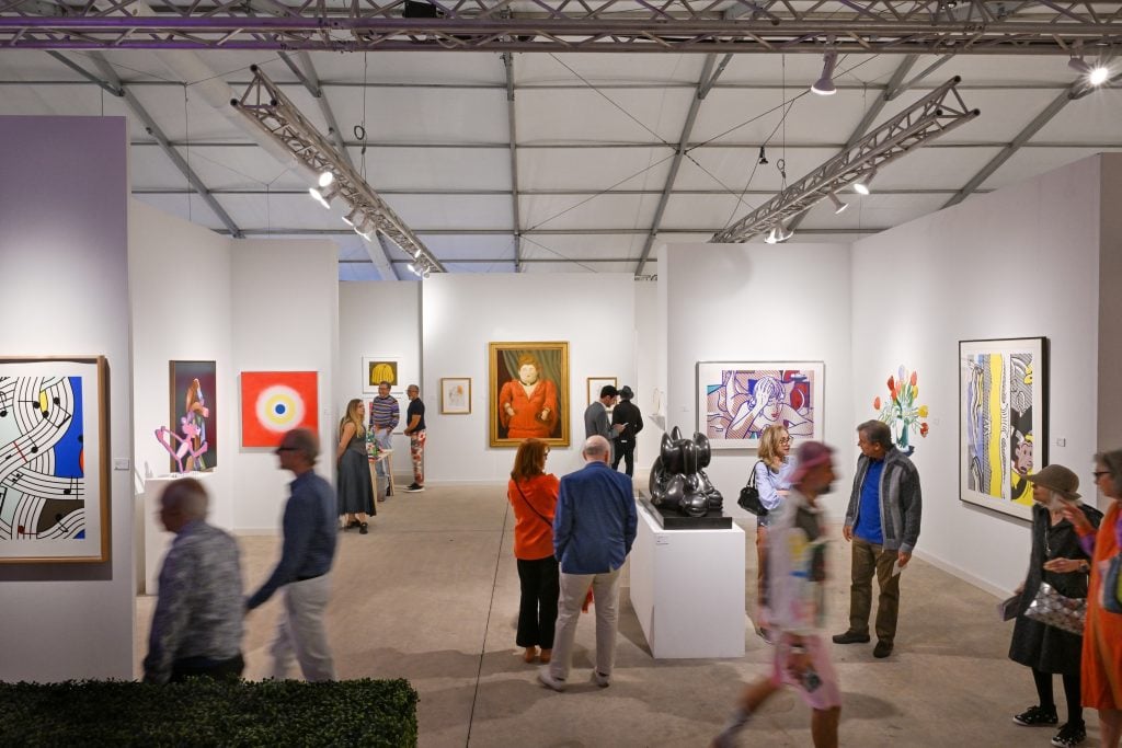 David Benrimon Fine Art's booth at Art Miami 2023 with various paintings installed on the booth walls and a pedestal with a bronze sculpture.