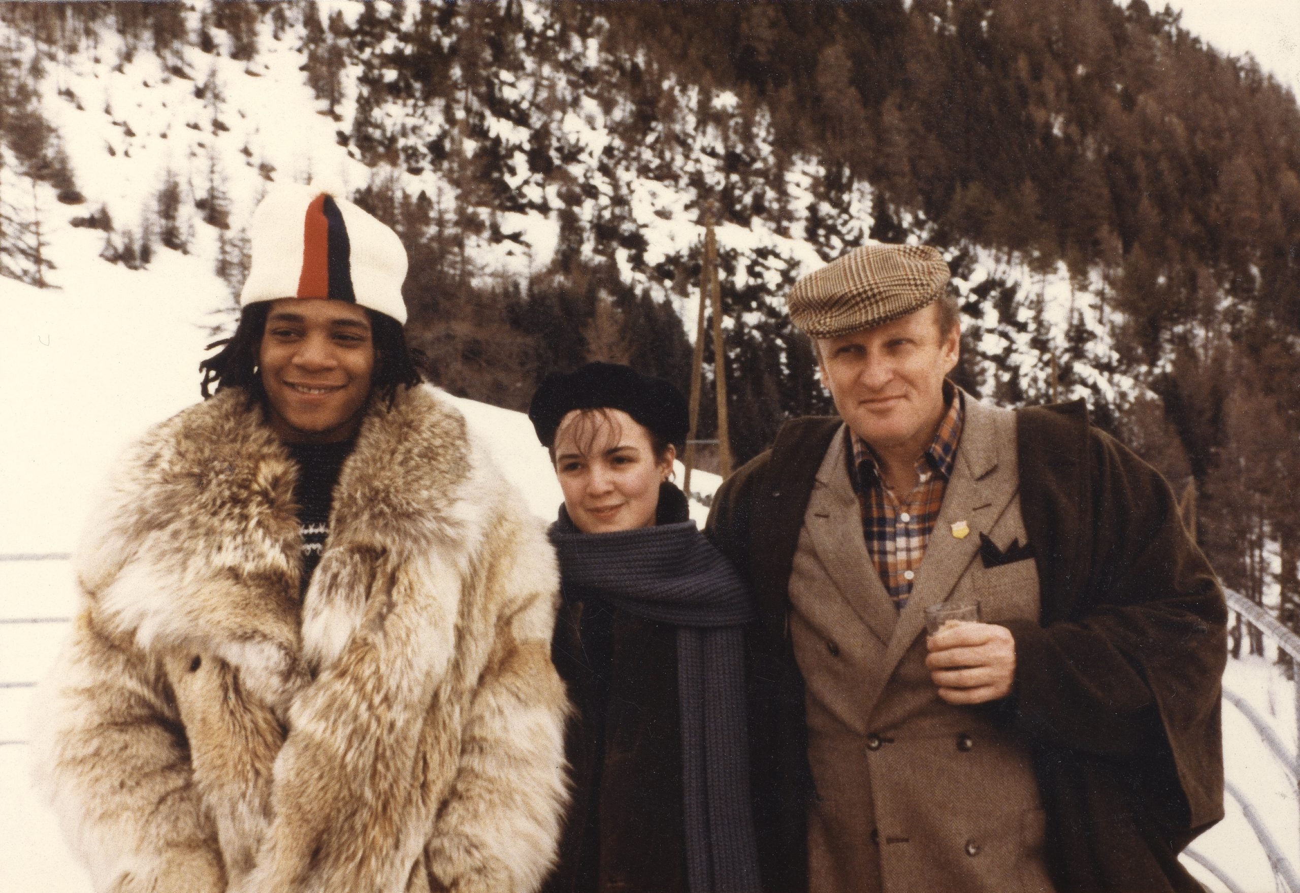 A photograph depicting three people standing outside amongst a snowy alpine terrain.