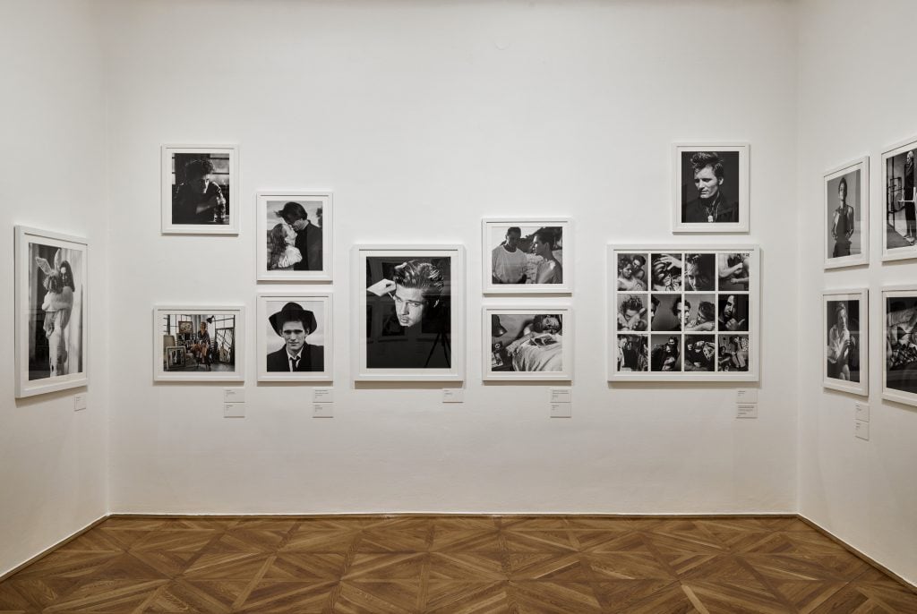 A gallery wall showcasing black-and-white celebrity portraits, including Brad Pitt, with parquet flooring below.