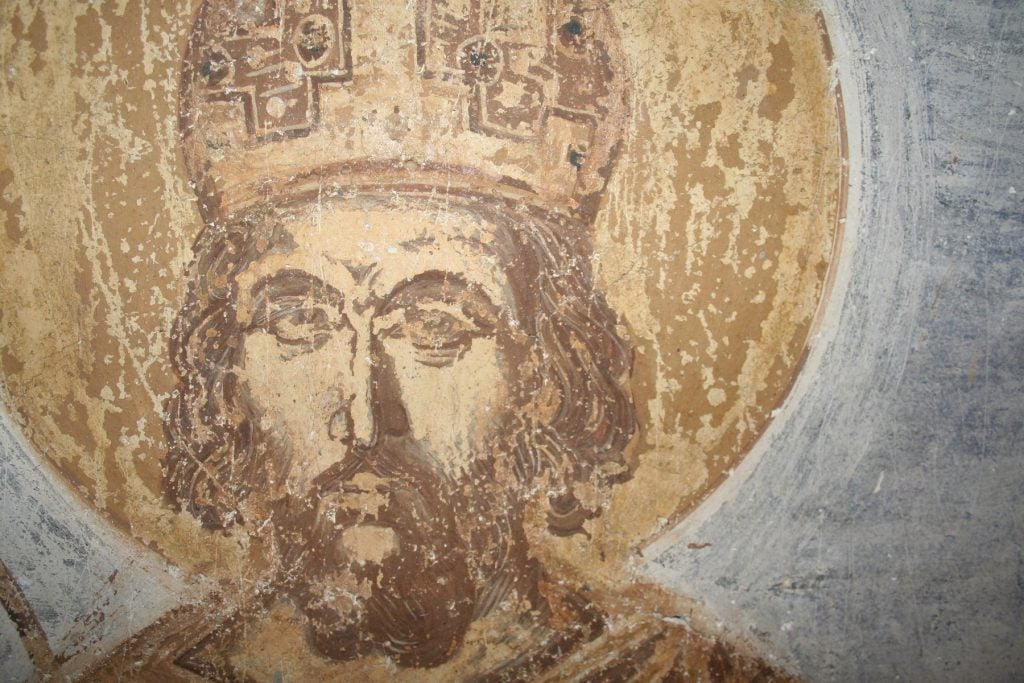 A close-up photograph of a 15th century fresco showing Emperor Constantine XI Palaiologos' head.