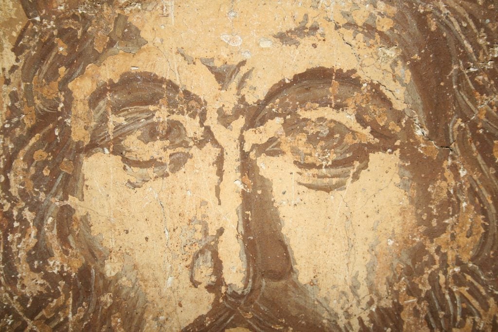 A close-up photograph of a 15th century fresco showing Emperor Constantine XI Palaiologos' eyes.