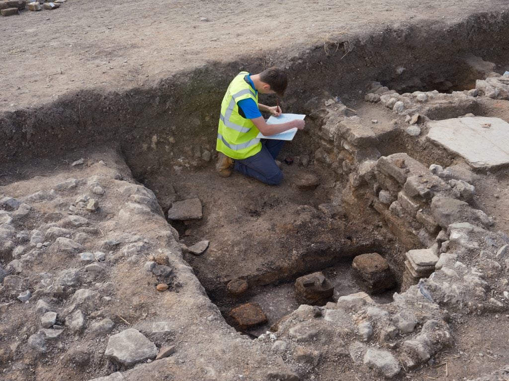 An archaeologist examines the remnants of a Roman villa's plumbing system.