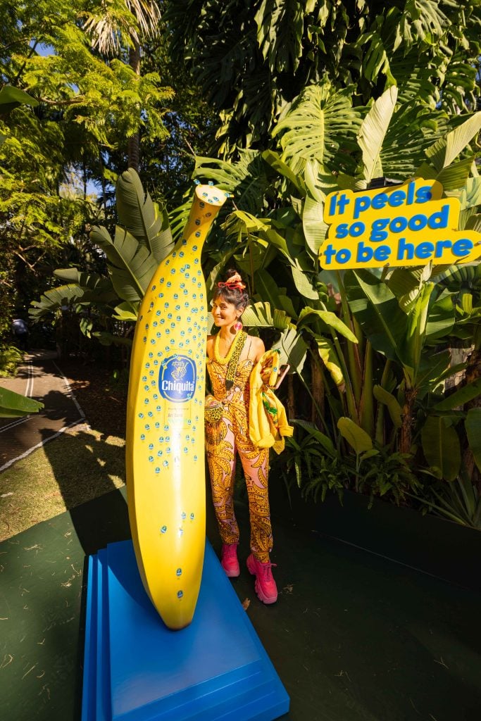 A woman poses with a giant banana at he Chiquita banana stand at Art Basel Miami Beach.