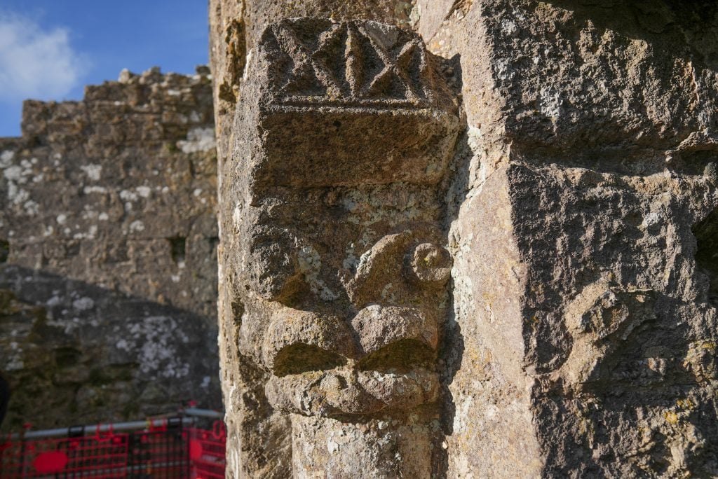 Close-up of intricate stone carvings on a weathered column at Corfe Castle in Dorset, England