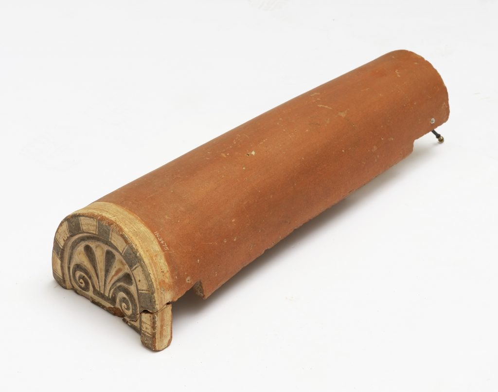 a tubular terracotta piece with a painting on one end