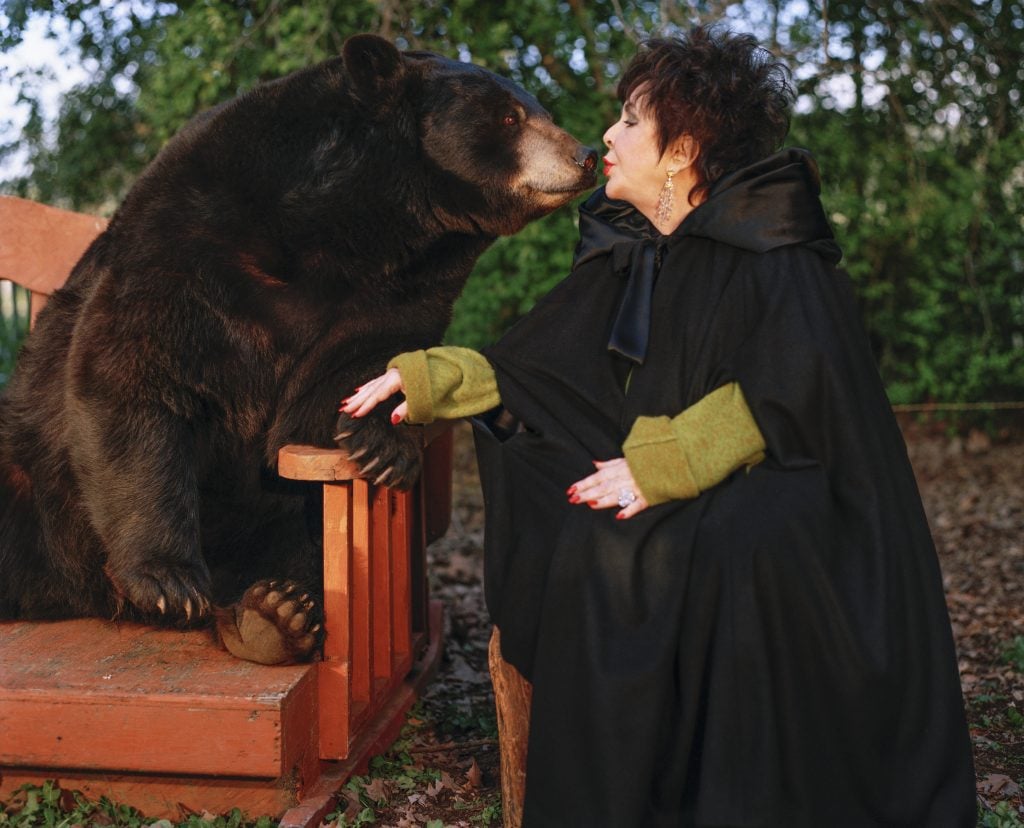 Bruce Weber photograph of Elizabeth Taylor, in a long black coat, leaning in to kiss a black bear