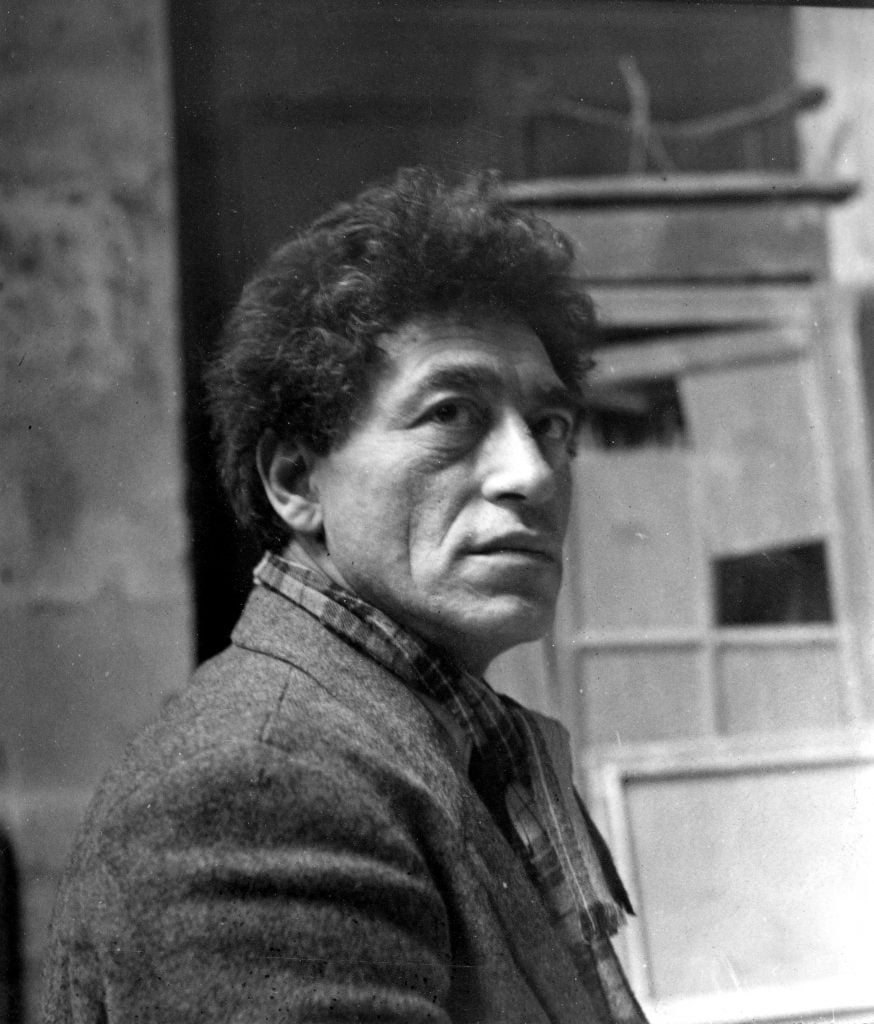 A monochrome photograph of Alberto Giacometti in his studio.