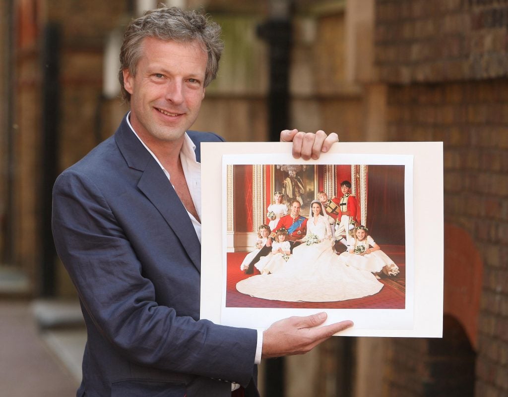 a man holds up picture with royal family in it