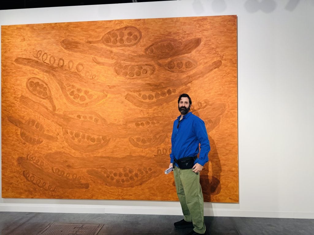 a man in a blue shirt stnsads in front of a large orange panting 