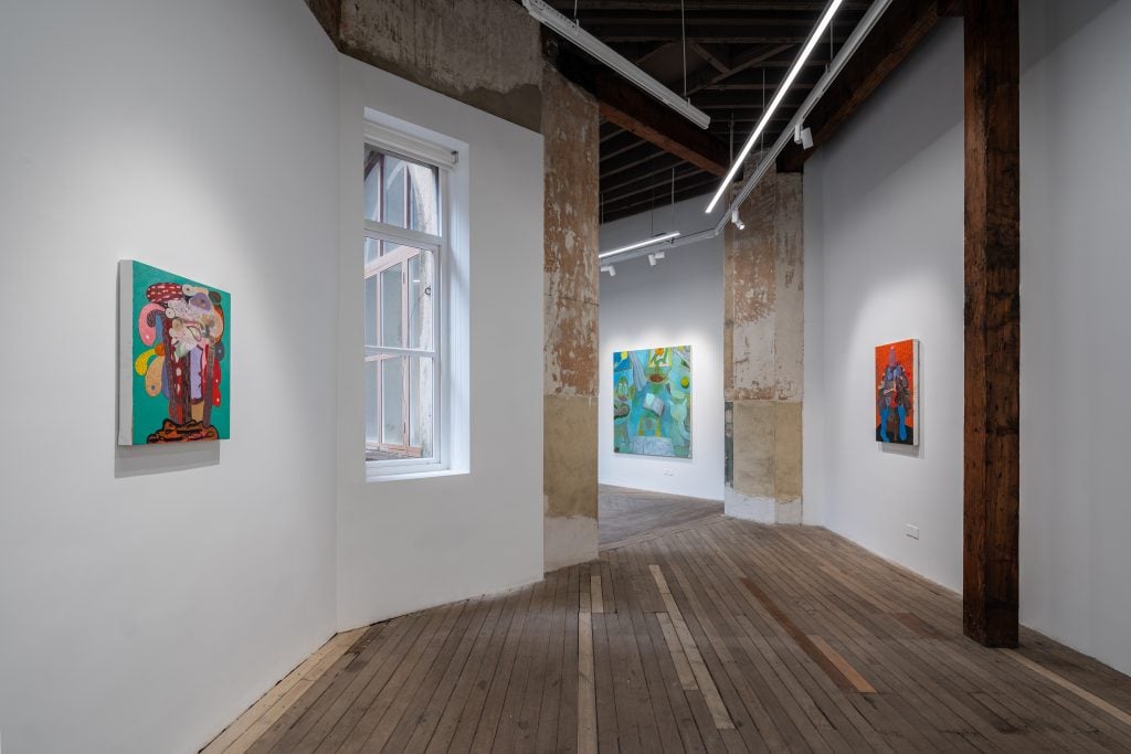 Installation view of Ivory Gate Gallery show in Shanghai with three paintings on a long narrow gallery with gray wooden floors.