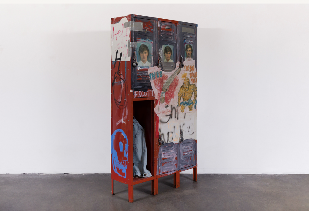 A photograph of a set of red lockers featuring messy collages atop a grey floor and before a plain white wall.