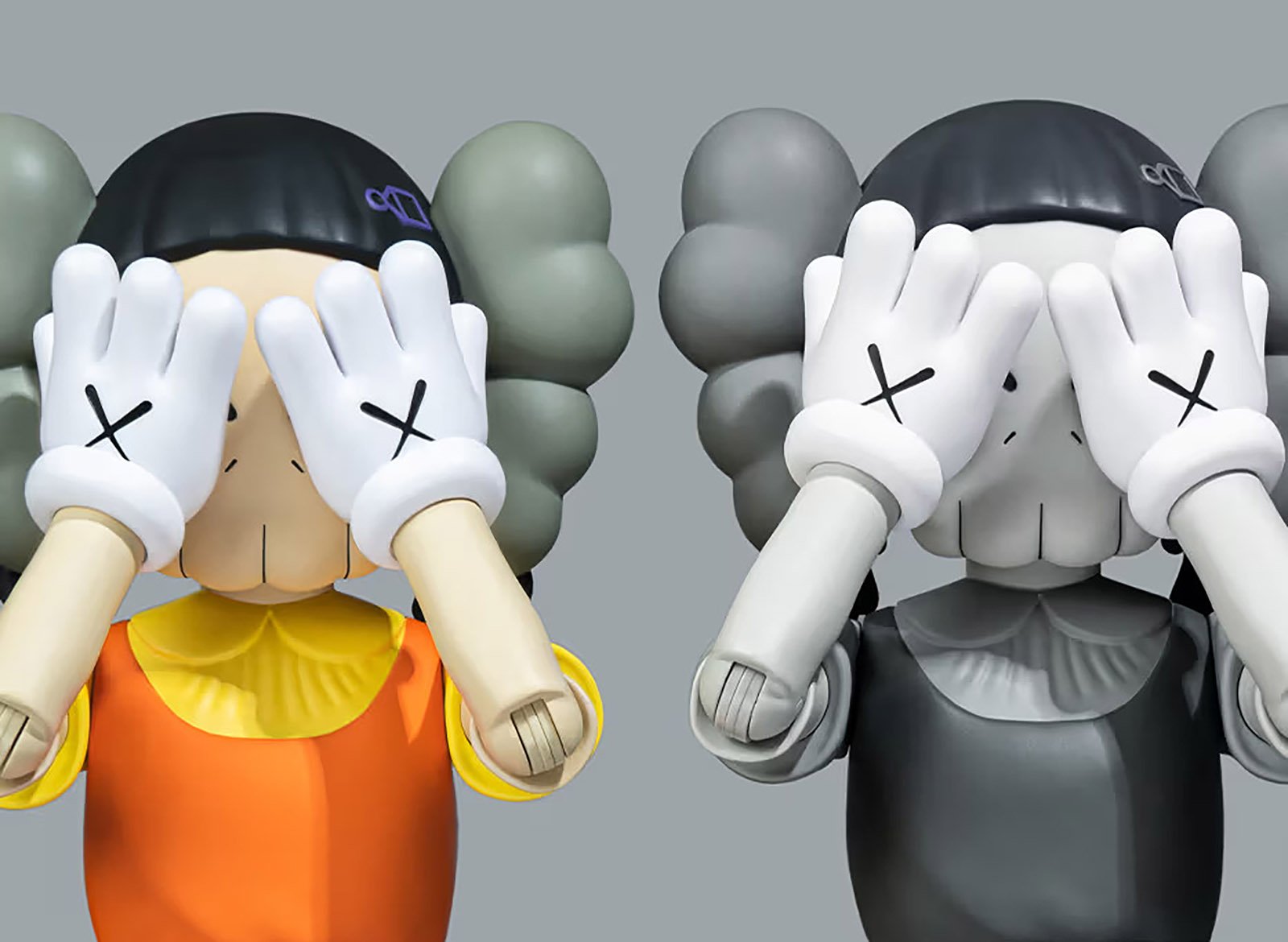 Two figurines by KAWS showing cartoon figures holding up their hands to their eyes