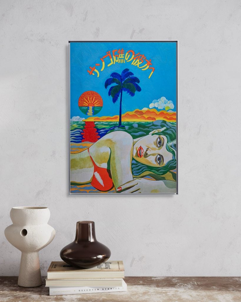 Keiichi Tanaami print of a woman laying in a swimsuit with teal hair beneath the outline of a palm tree, stylized sea, and Japanese text in rainbow installed above a rustic table with two ceramic vessels and a stack of three books.